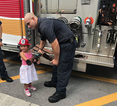 Little girl with firefighter in front of fire truck