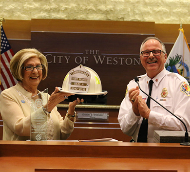 Commissioner Feuer holding fire hat next to Fire Chief