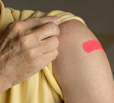 Person with sleeve rolled up and band aid on upper arm