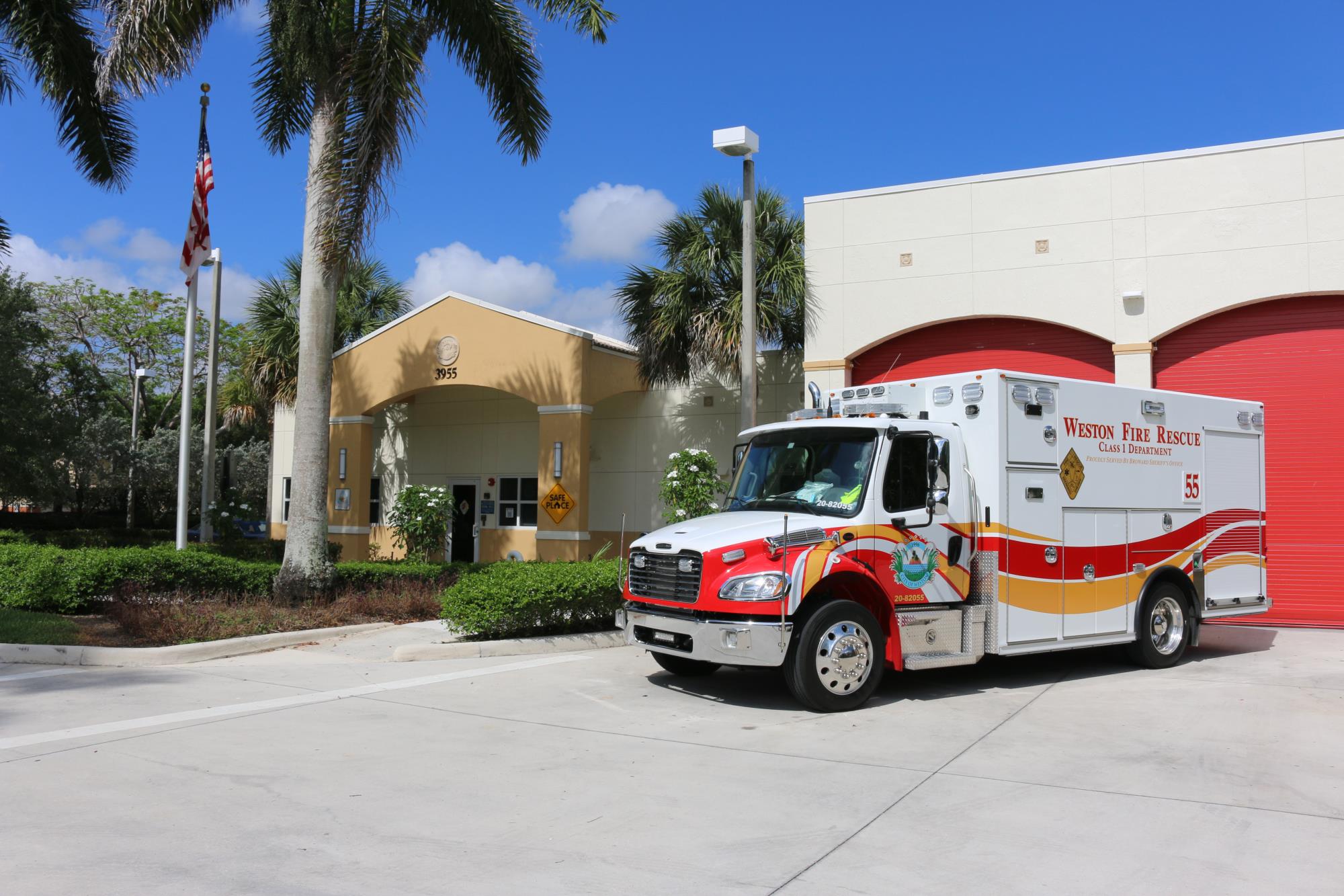 Fire Station 55 on a sunny day with an emergency vehicle in front of the red garage.