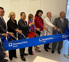 Seven people behind large blue ribbon with scissors for Cleveland Clinic Weston Ribbon Cutting on Dec. 14, 2022