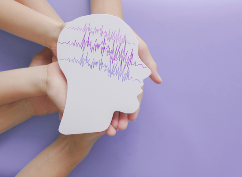 Hands holding a paper head with lines with purple background