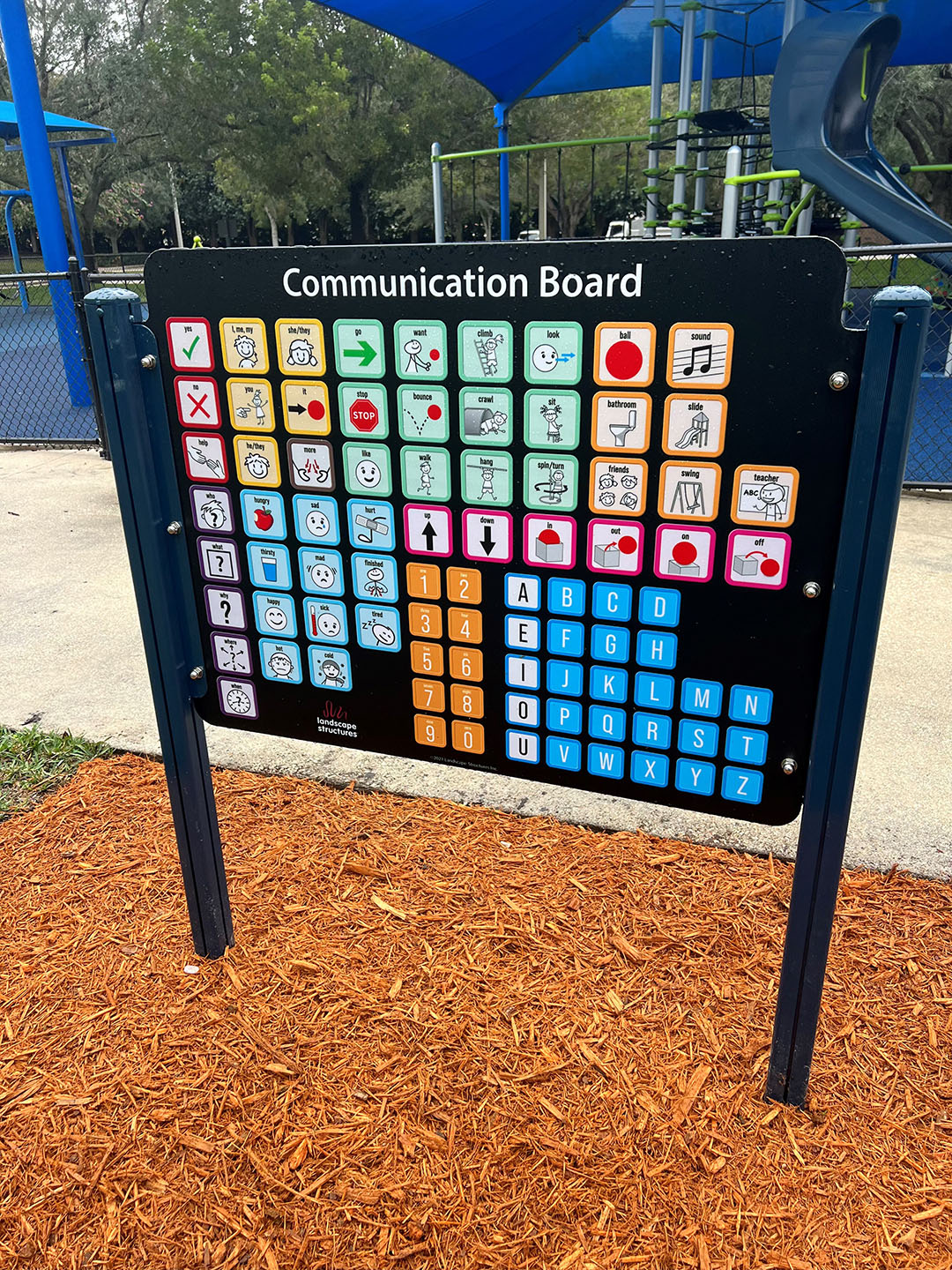 Communication Board at Emerald Estates Park in mulch in front of playground