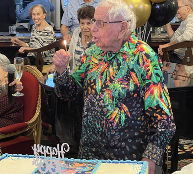 100 year old Louis Miller blows out candle from cake